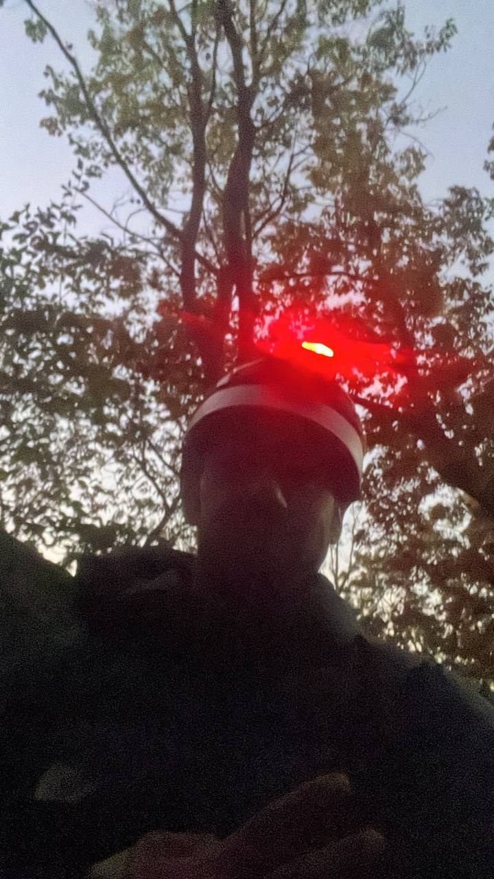Selfie under the overcast sky at the crag, hard hat light glowing in the low light