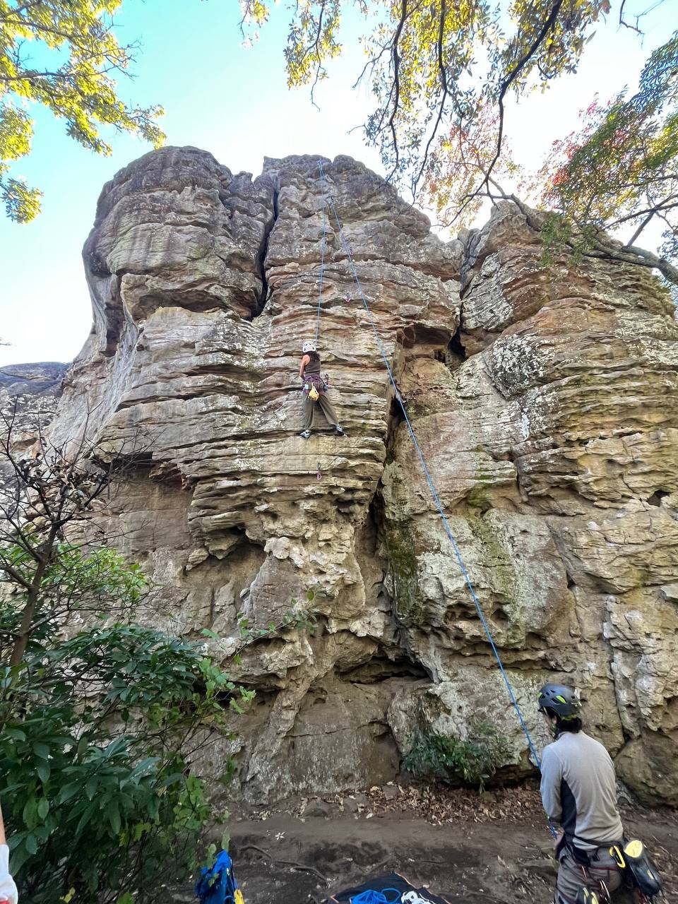 Climber working the sandstone face with a partner belaying below