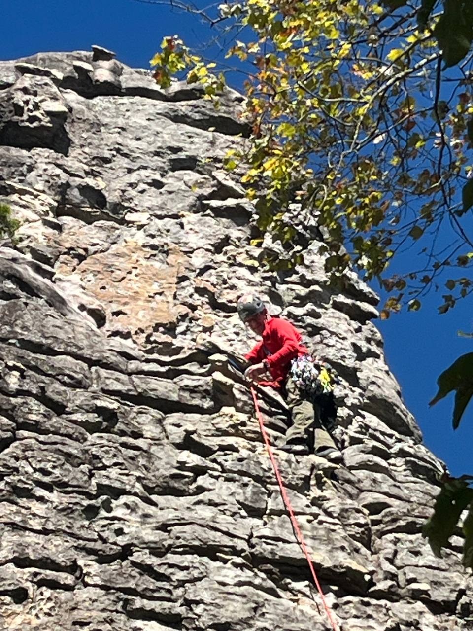 Climber in a red shirt working a steep gray rock face