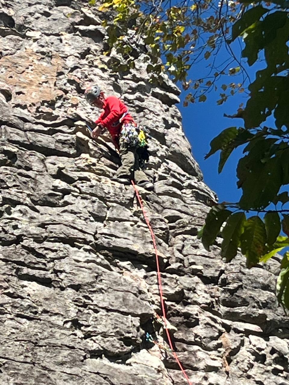 Climber mid-ascent on the fractured gray rock
